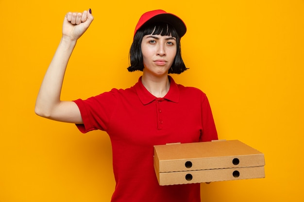 Zelfverzekerde jonge blanke bezorger die pizzadozen vasthoudt en haar vuist opheft