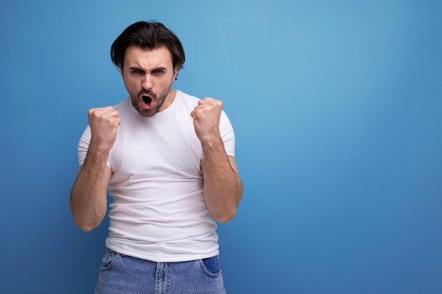 Zelfverzekerde jonge brunette man in een witte t-shirt en spijkerbroek