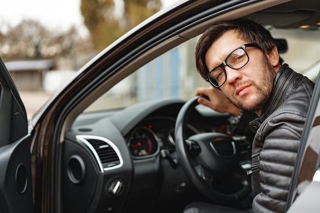 Zelfverzekerde jonge man zit in een auto