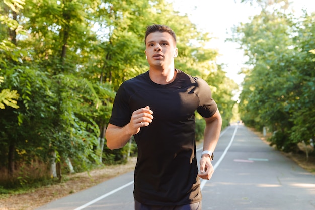 Zelfverzekerde jonge shirtless sportman in oortelefoons lopen