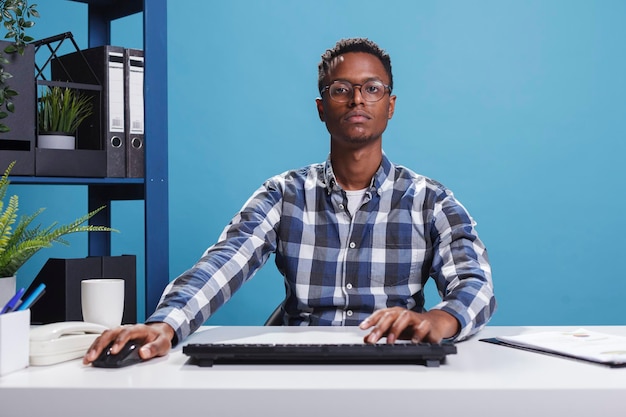 Zelfverzekerde jonge volwassen zakenman die computertoetsenbord en muis gebruikt om aan de presentatie van het opstartproject te werken. Teamleider financiële afdeling van marketingbureau werkt aan managementplan tijdens het gebruik van pc.