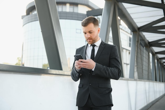 Zelfverzekerde jonge zakenman die mobiele telefoon in de stad gebruikt