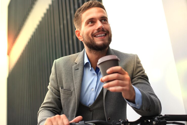 Foto zelfverzekerde jonge zakenman met zijn fiets die buiten koffie drinkt
