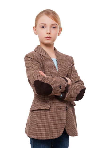 Zelfverzekerde kleine leider. Zelfverzekerd klein meisje in formalwear met gekruiste armen terwijl ze geïsoleerd op wit staat