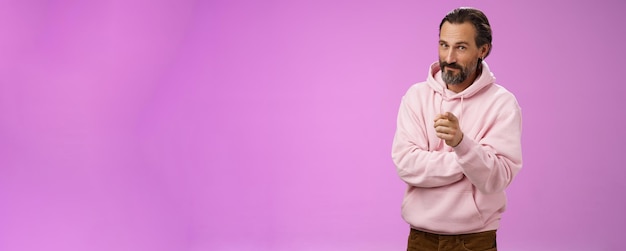 Zelfverzekerde, knappe, charismatische, volwassen, baarde man in een stijlvolle roze hoodie die je uitnodigt om mee te doen.