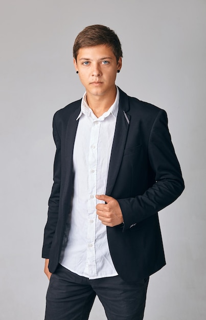Zelfverzekerde knappe jonge zakenman in een stijlvol jasje dat over een witte achtergrond staat