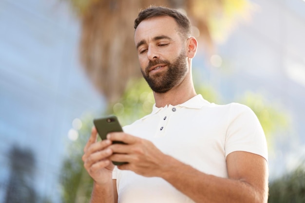 Zelfverzekerde knappe latijnse man die mobiele app gebruikt om online op straat te winkelen