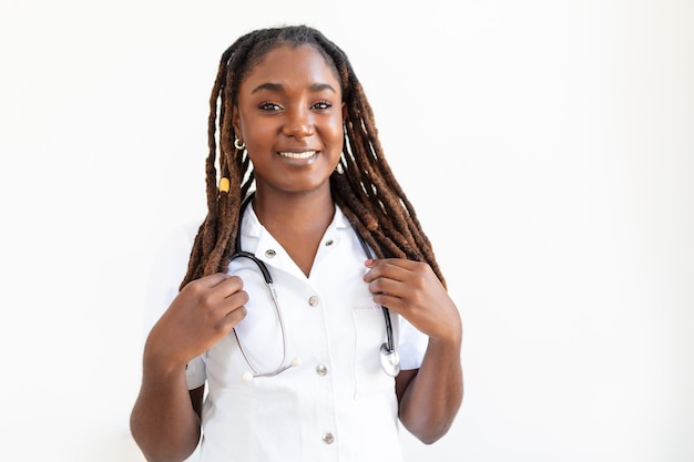 Zelfverzekerde lachende arts poseren en kijken naar camera met stethoscoop in haar handen vriendelijke afro-amerikaanse vrouwelijke arts lachend arts met stethoscoop om haar nek