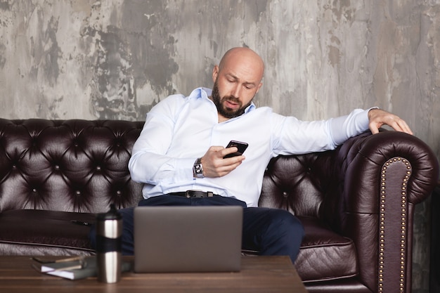 Zelfverzekerde man correspondeert met collega's in de messenger aan de telefoon