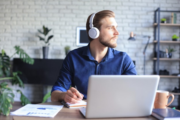 Zelfverzekerde man met een headset die spreekt en kijkt naar zakelijke webinar-training, luisterend naar lezing.