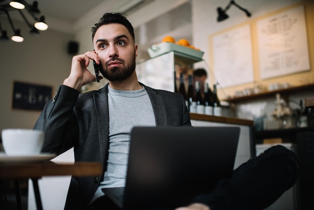 Zelfverzekerde man met laptop met telefoongesprek