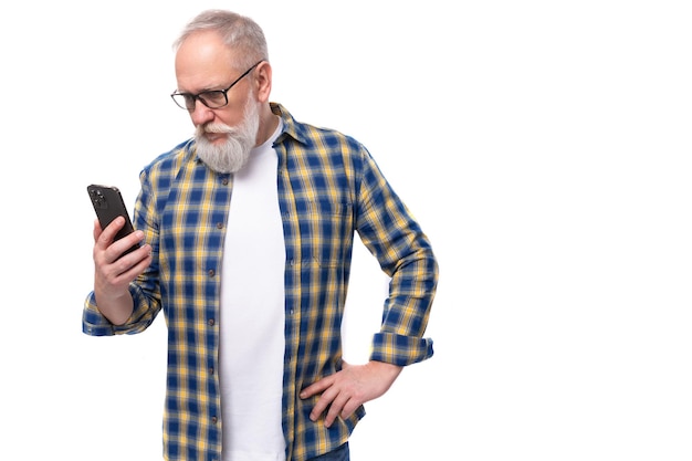 Zelfverzekerde slimme senor grijsharige gepensioneerde man met snor en baard communiceert in smartphone
