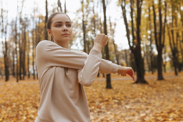 Zelfverzekerde sportvrouw die armen strekt en traint tijdens de training in het herfstpark