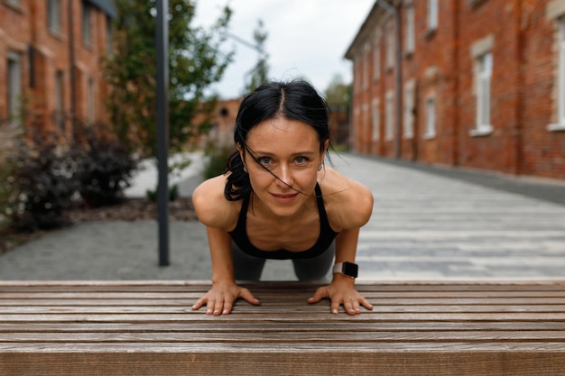 Zelfverzekerde sportvrouw doet push-ups vanaf de bank buiten