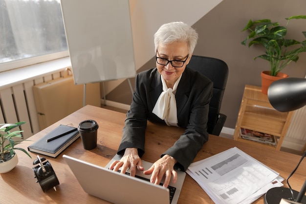 Zelfverzekerde stijlvolle Europese senior vrouw van middelbare leeftijd met behulp van laptop op de werkplek stijlvolle oudere volwassen s