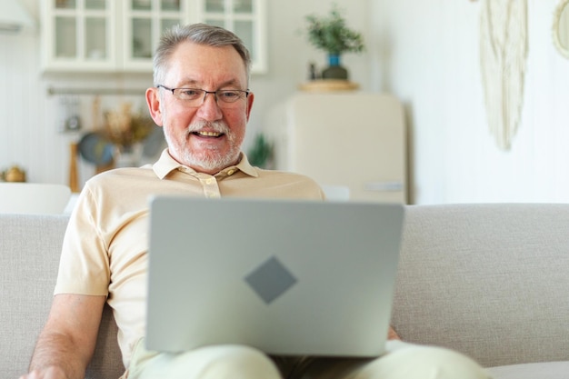 Zelfverzekerde, stijlvolle, gelukkige senior man van middelbare leeftijd die thuis een laptop gebruikt. Stijlvolle oudere volwassen baardgra