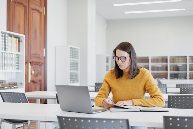 Zelfverzekerde vrouw werkt in bibliotheek in coworking op laptop of kantoor vrouwelijke student studeert online