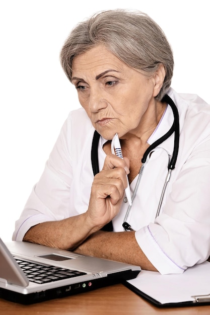 Zelfverzekerde vrouwelijke arts zittend aan tafel met laptop