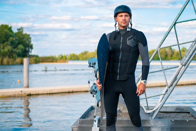 Zelfverzekerde wakeboarder die op de pier staat met een bord in de hand