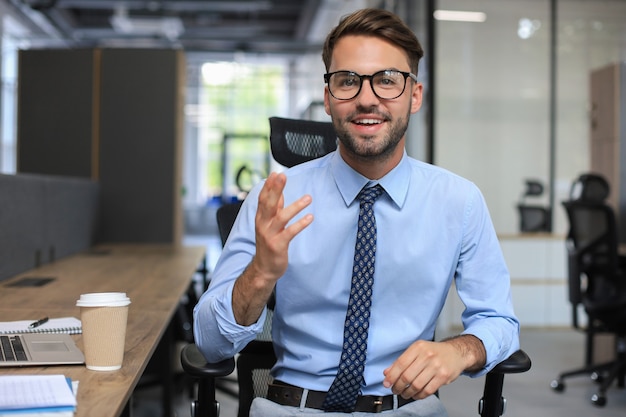 Zelfverzekerde zakenman die naar de camera kijkt en praat over de bedrijfsstrategie en het businessplan, waarin het bedrijfssucces wordt uitgelegd.