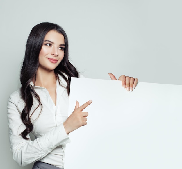 Zelfverzekerde zakenvrouw die lacht en een witte lege bordachtergrond toont met kopieerruimte voor reclamemarketing of productplaatsing Succesvolle zakelijke dame portret