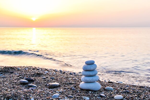 Foto zen-achtige stenen piramide op het strand bij zonsopgang