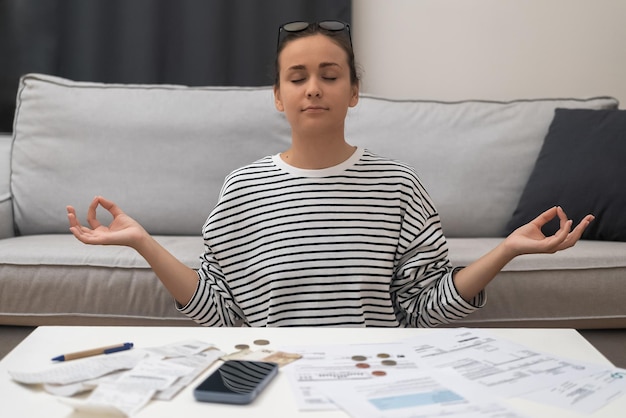 Фото Женщина, занимающаяся финансами, медитирует, находит спокойствие после финансового стресса, рассчитывает счета за коммунальные услуги и налоги