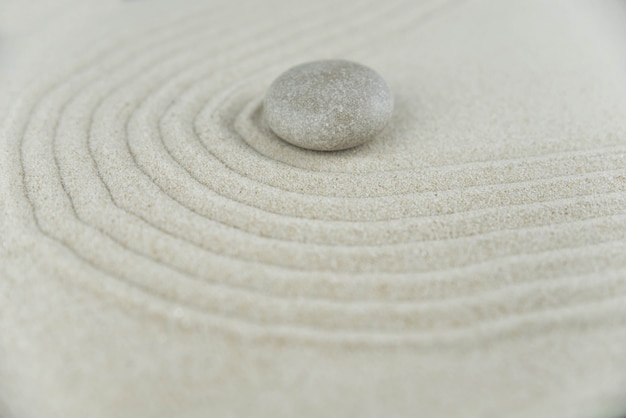 Zen garden. Pyramids of white and gray zen stones on the white sand with abstract wave drawings. 