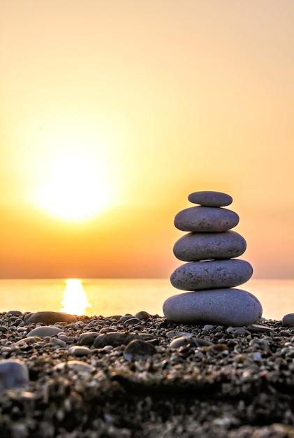 Foto piramide di pietra zen sulla spiaggia al tramonto at