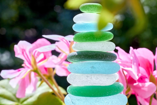 Foto piramide zen di pietre di vetro su uno sfondo di fiori nel giardino