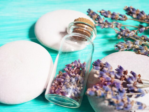 Zen stack stones on a blue wooden background, lavender seeds in a bottle and lavender branches nearby.