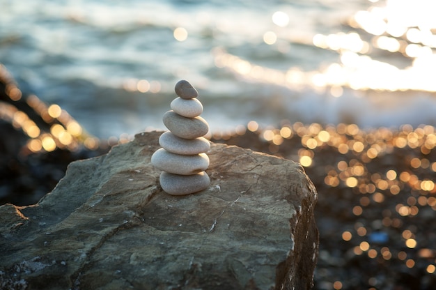 Zen stenen piramide aan de kust in de ondergaande zon