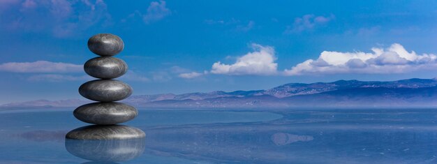 Zen stones row from large to small in water with blue sky 3d illustration