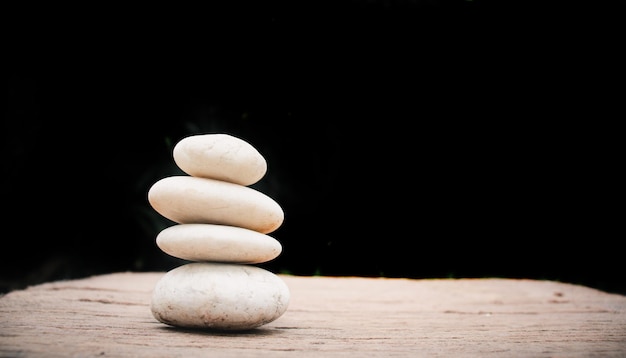 Photo zen stones on wooden on black backgroundconcept relaxationzenspring