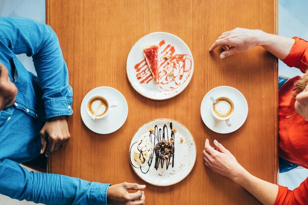 レストランでコーヒーとケーキを飲む前のカップルの天頂の景色