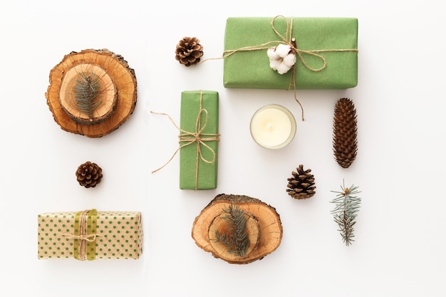 Photo zero waste christmas composition background made of pine cones, branches, candle, tree rings, crafted gifts with no plastic on white table. top view, close up, copy space, background, flat lay.