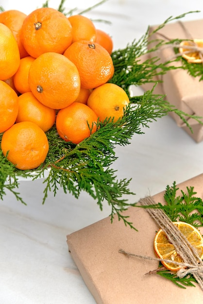 Фото Безотходные рождественские подарки, завернутые в бумагу, украшенные веткой туи и сушеными апельсинами