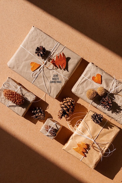 Zero waste Christmas knolling flat lay with hard shadows Hand crafted eco gift natural New Year jute decorations top view Kraft paper wrapping without plastic concept Orange zest treeheartscones