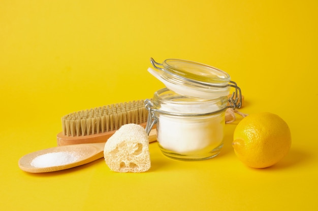 Zero waste cleaner, soda can, wooden brush, lemon, citric acid and loofah on yellow background