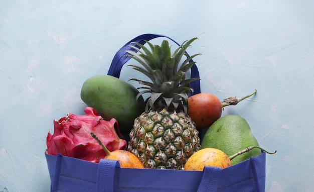 Foto zero waste concept blauwe boodschappentas van textiel met tropische vruchten, mango, ananas, draak en passievrucht