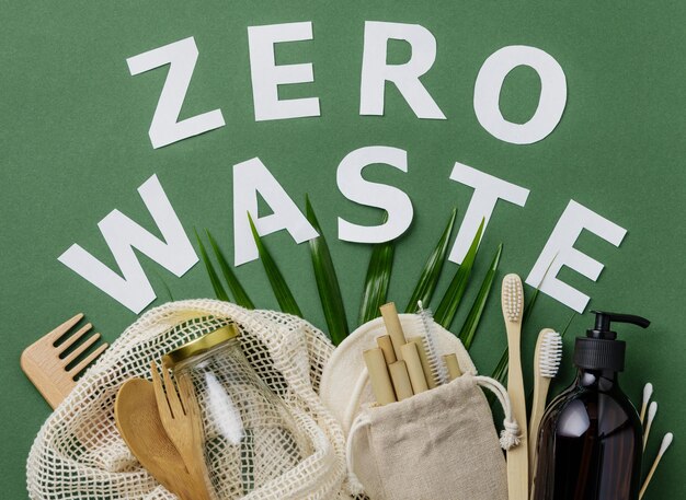 Zero waste concept Cotton bag bamboo cultery glass jar bamboo toothbrushes hairbrush and straws on green background