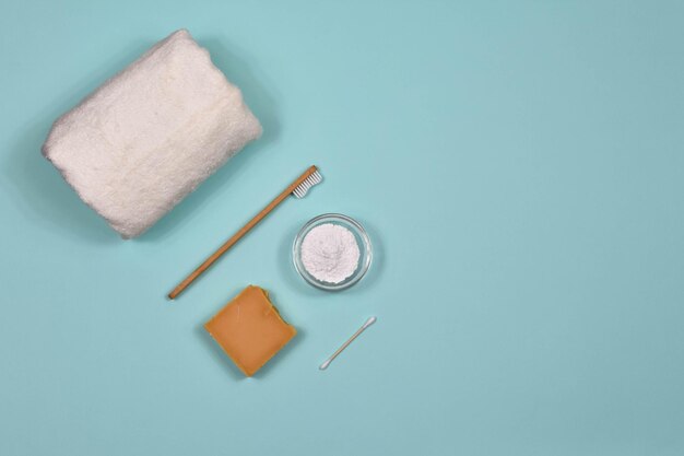 Zero waste concept Toothbrush tooth powder towel and soap on a blue background Ecofriendly bamboo toothbrush View from above