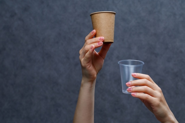 Zero waste concept. Wooden cutlery versus plastic cutlery. Eco-friendly disposable tableware made of bamboo wood and paper on a gray background. Caring for the environment. Recycling problem.