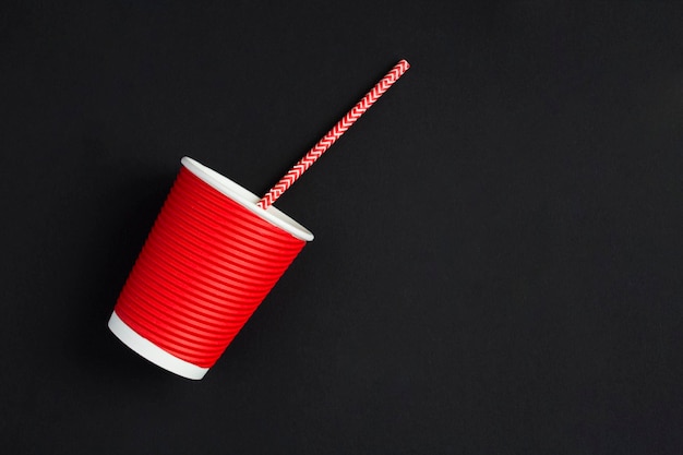 Zero waste Disposable red paper cup and drinking straw on black background Top view Copy space