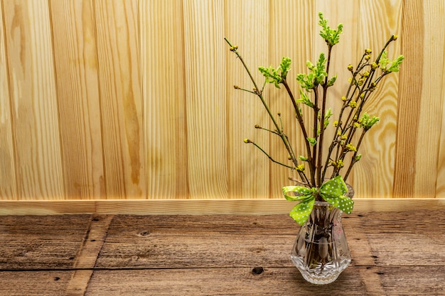 Zero waste Easter concept. Spring twigs with fresh green leaves. Glass vase, polka dot ribbon bow.