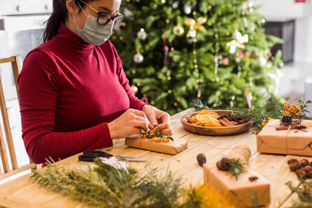 Zero waste en eco-stijl gerecyclede kerstcadeaus Vrouw met medicijnmasker pakt geschenkdozen in