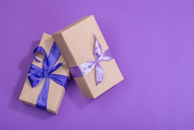 Zero waste gift concept wrapped in craft paper surprise box for anniversary mothers or valentines day happy birthday greeting card purple background flat lay top view