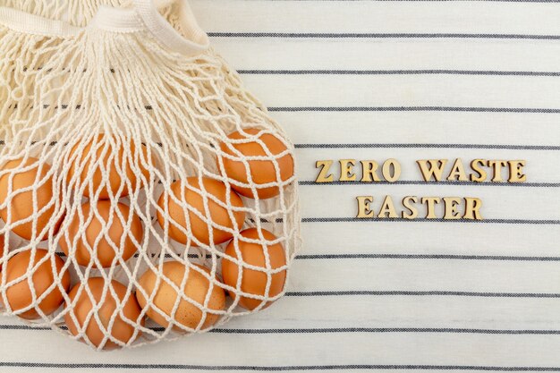 Zero waste pasen-concept. geen plastic zakconcept. minimalistische stijl. beige mesh boodschappentas met bruine kippeneieren op textiel achtergrond.