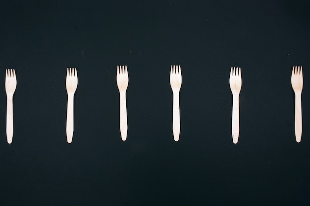 Zero waste. Plastic free. Eco friendly natural wooden forks in the row on dark, top view.