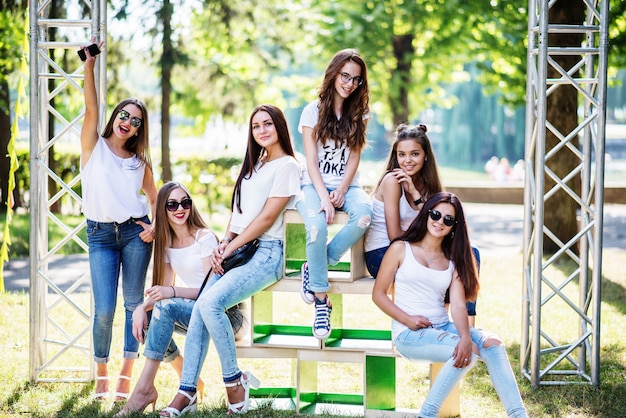 Zes prachtige modelvrouwen die op houten dozen in het park op een zonnige dag stellen.